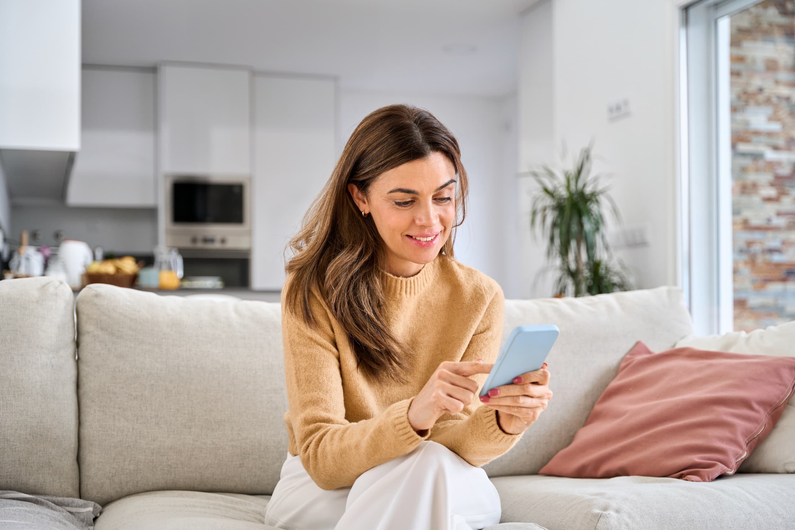 blog/Woman sits on couch and connects her phone to Wi-Fi